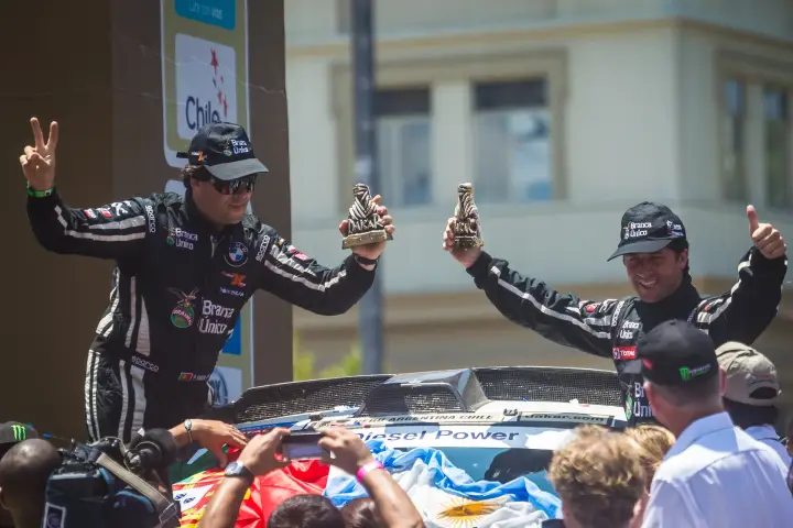 Dakar Rally 2013: drivers celebrating on car holding Dakar trophies