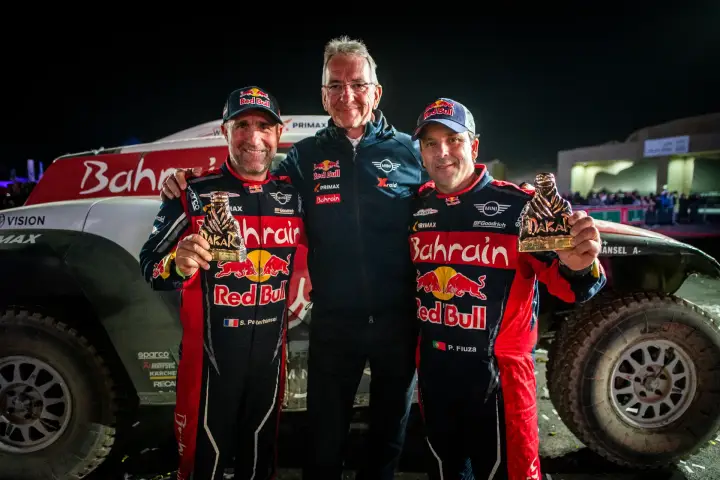 Dakar Rally 2020: three people posing with Dakar trophies at night