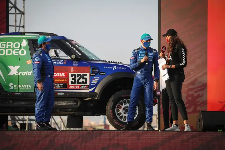 Dakar Rally 2021: two drivers being interviewed beside car on stage