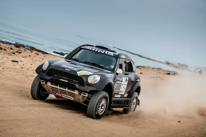 Rallye du Maroc 2016: black Mini racing on sandy beach near ocean